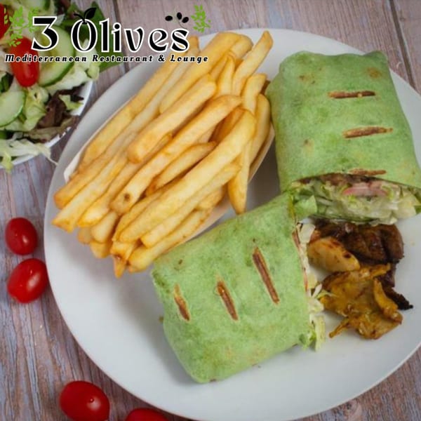 Two green wraps with grilled marks, fries, and salad on a white plate, with cherry tomatoes.